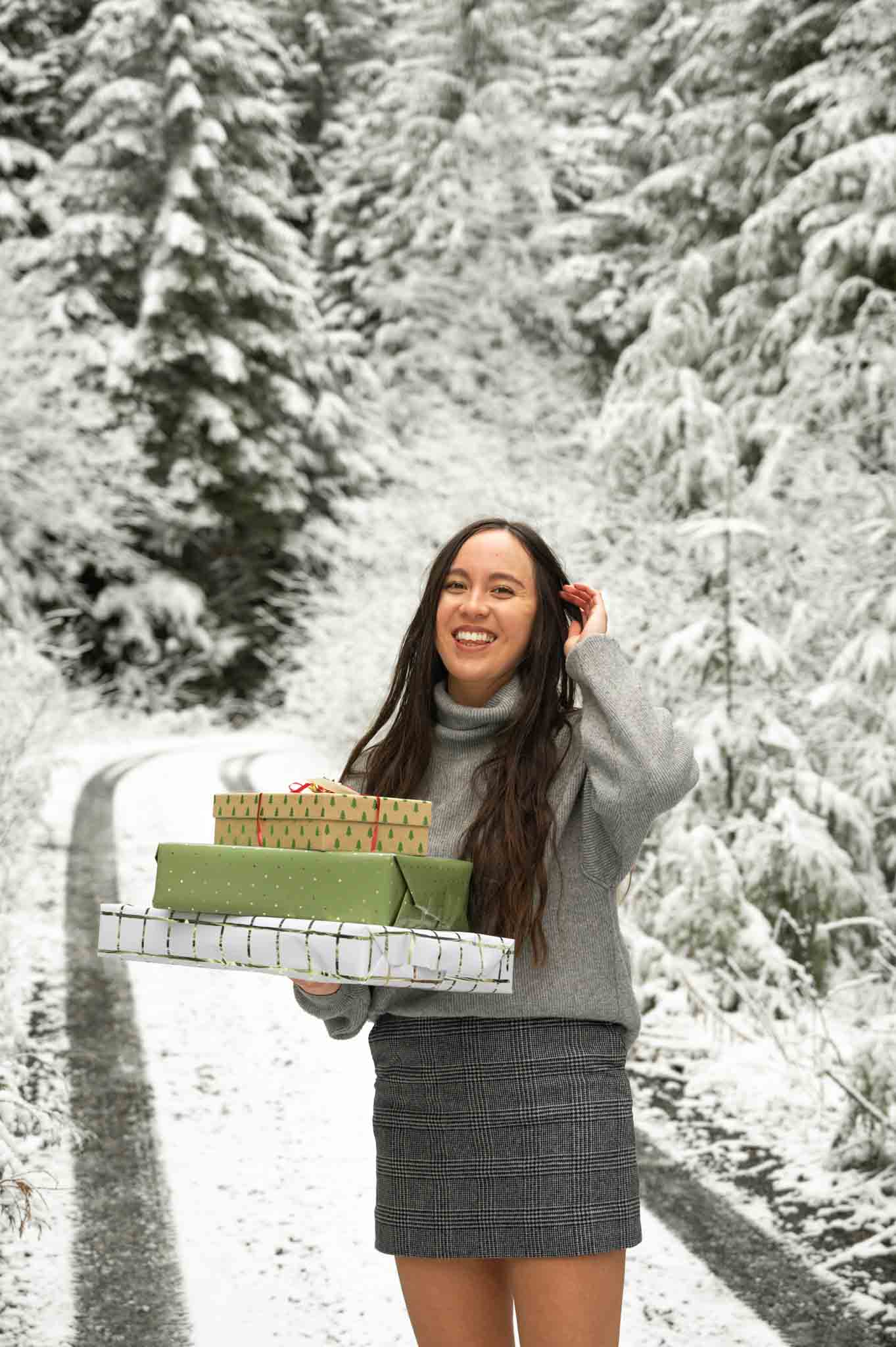 Pacific Northwest lifestyle blogger holding holiday presents in a snowy scene, and sharing travel gifts for women
