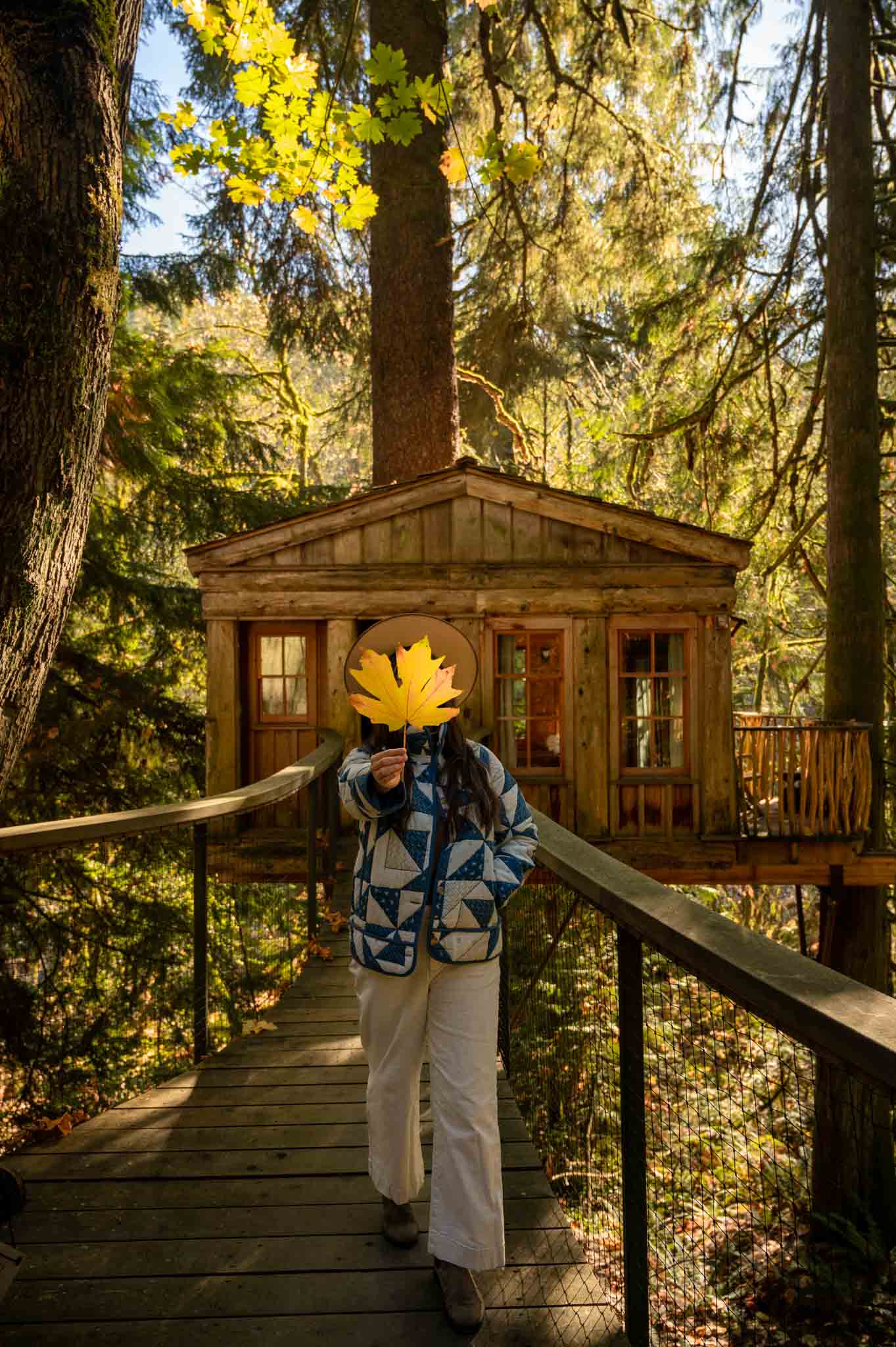 Travel content creator Kara Patajo holding up a leaf in front of Temple of the Blue Moon at TreeHouse Point Washington